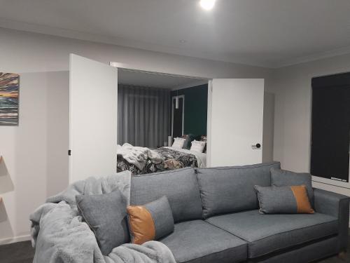 a living room with a gray couch and a bedroom at 44onRoaring - in the Huon Valley in Surveyors Bay