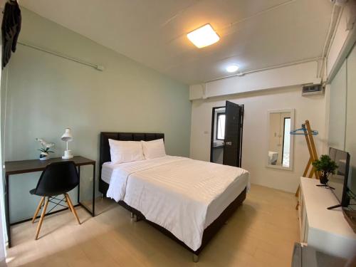 a bedroom with a bed and a desk and a television at Baan Ploy In in Chiang Mai