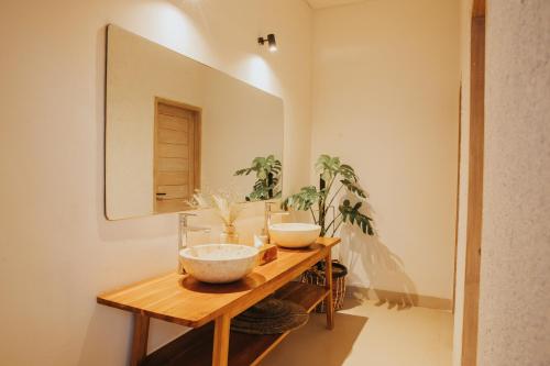 a bathroom with two bowls on a wooden table with a mirror at Ratan Uluwatu Hotel and Villas in Uluwatu