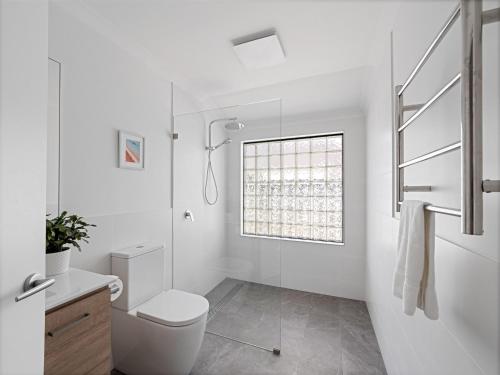 a white bathroom with a toilet and a window at Clearwater Escape Dunsborough in Dunsborough