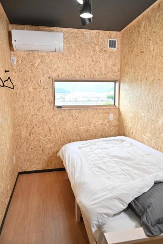 a small bedroom with a bed and a window at ｹﾞｽﾄﾊｳｽ ﾊﾞｲｸﾔﾉﾆｶｲ in Hagi