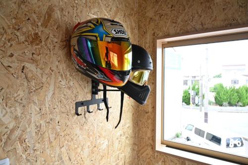 a helmet hanging on a wall next to a window at ｹﾞｽﾄﾊｳｽ ﾊﾞｲｸﾔﾉﾆｶｲ in Hagi