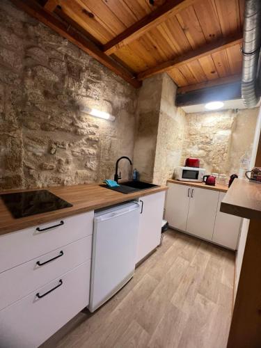 - une cuisine avec des placards blancs et un mur en pierre dans l'établissement Centre historique quartier piéton, à Montpellier
