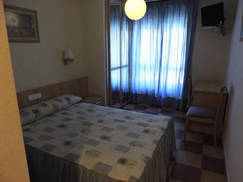 a bedroom with a bed and a chair and a window at Mirasierra in Bustarviejo