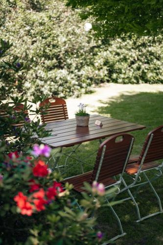 a wooden picnic table with two chairs and flowers at Landgasthof-Unter den Linden in Oelixdorf