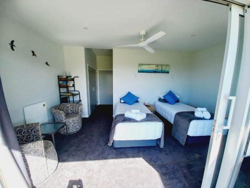 a hotel room with two beds and a chair at Moko Hiwi Escape - Kotare Suite in Ruakaka
