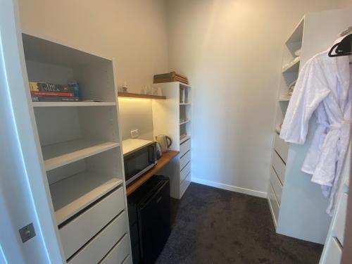 a room with a closet with a tv and shelves at Moko Hiwi Escape Ruakākā- Huia Suite in Ruakaka