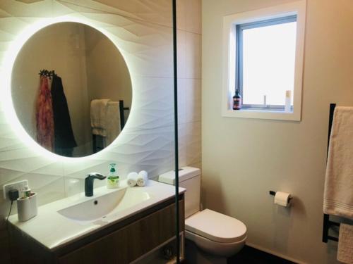 a bathroom with a sink and a toilet and a mirror at Moko Hiwi Escape Ruakākā- Huia Suite in Ruakaka