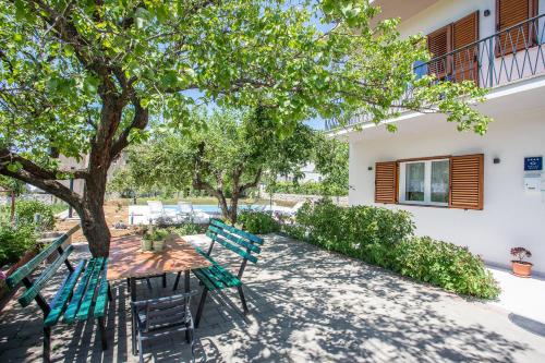 a patio with two green chairs under a tree at Villa Knez in Gata
