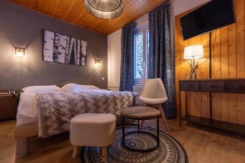 a bedroom with a bed and two chairs and a television at Hotel du Lac in Crans-Montana