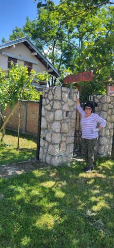 a man standing next to a stone wall with a street sign at Apartmani Tina - Srebrno jezero in Zatonje