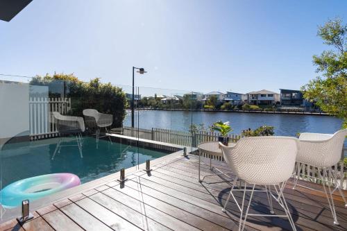 a deck with chairs and a swimming pool on a balcony at Luxury Lakeside Living at Birtinya in Kawana Waters