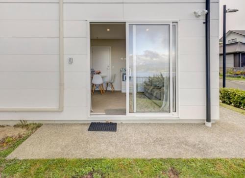 a white house with a sliding glass door at Stunning Seaviews in Wellington