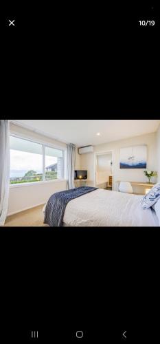a bedroom with a large bed with a large window at Stunning Seaviews in Wellington