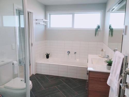 a bathroom with a tub and a toilet and a sink at Stunning Seaviews in Wellington