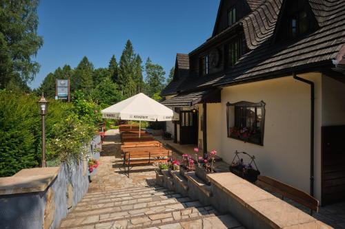a patio with wooden benches and a white umbrella at Villa Biesisko Przysłup Cisna in Cisna