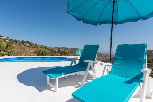 two chairs and an umbrella next to a swimming pool at Charming Villa in Competa with Private Pool in Cómpeta