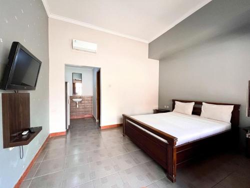 a bedroom with a bed and a flat screen tv at Prabhu Suites in Lovina