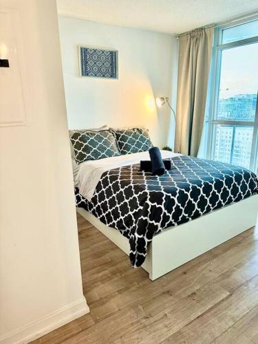una camera da letto con un letto bianco e nero e una finestra di Stylish Condo Downtown Near CN Tower - Free parking a Toronto