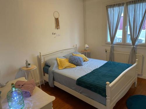 - une chambre avec un lit doté d'oreillers jaunes et bleus dans l'établissement Appart, chantier naval, très cosy et vintage, à Saint-Nazaire