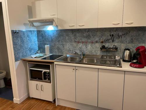 une cuisine avec des armoires blanches et un évier dans l'établissement Appart, chantier naval, très cosy et vintage, à Saint-Nazaire