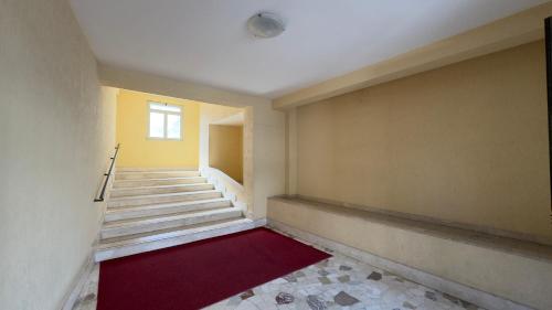 an empty hallway with stairs and a red rug at Policlinic House Messina in Messina