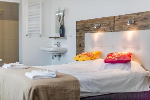 a bedroom with a bed with two pillows and a sink at Dijkstra Hotels in Bergen