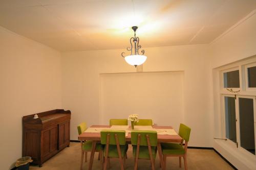 a dining room with a table and green chairs at Lulu's Bungalow in Nuwara Eliya