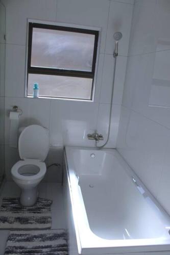 a bathroom with a tub and a toilet and a window at KT Space in Midrand