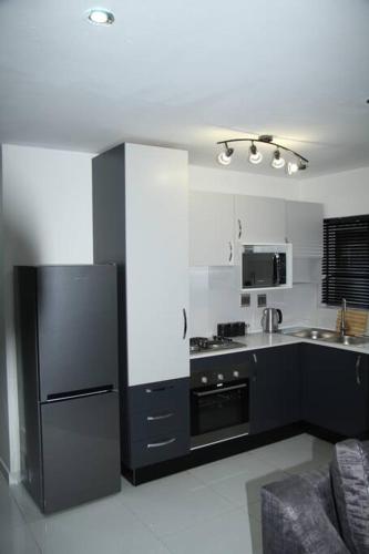 a kitchen with a black refrigerator and a sink at KT Space in Midrand