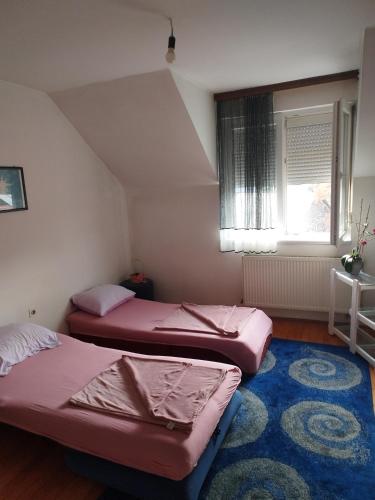 two beds in a room with a window and a rug at Parovic in Nevesinje