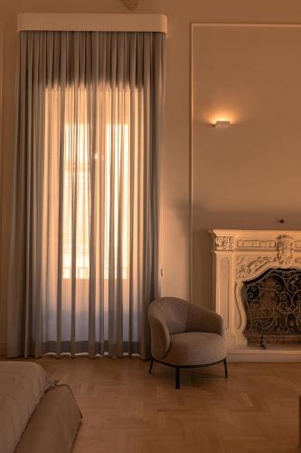 a bedroom with a bed and a chair and a fireplace at Palazzo Zimara Boutique Hotel in Lecce