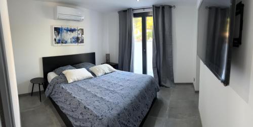 une chambre avec un lit avec une couette bleue et une télévision dans l'établissement Ô portes de Figuerolles, à Martigues