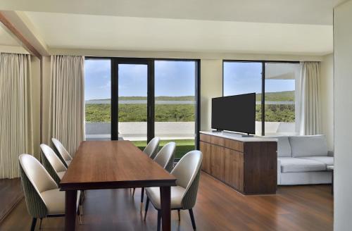 a living room with a table and a tv and chairs at Courtyard by Marriott Mahabaleshwar in Mahabaleshwar