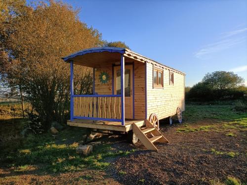 a wooden tiny house sitting in a field at Roulottes - Les lits de berger in Saint-Front