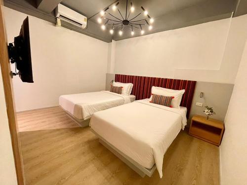 a bedroom with two beds and a television and a chandelier at At Thaphae Hostel in Chiang Mai