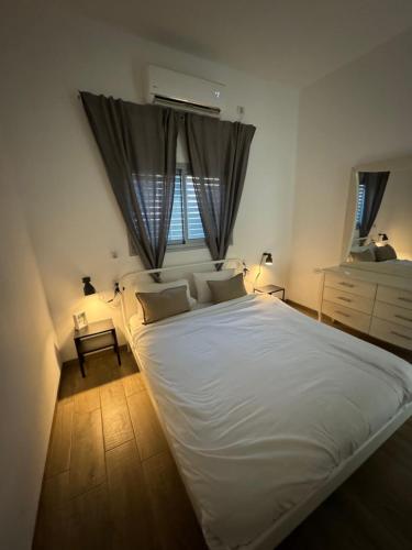 a large white bed in a bedroom with two windows at בית בעמק בעיצוב מודרני וחמים in Bet Sheʼan