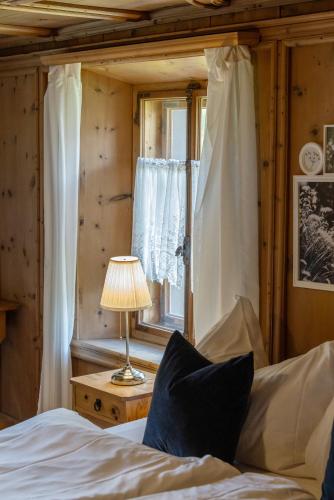 a bedroom with a bed with a lamp and a window at Chesa-strimer - Stüva Sur in La Punt-Chamues-ch