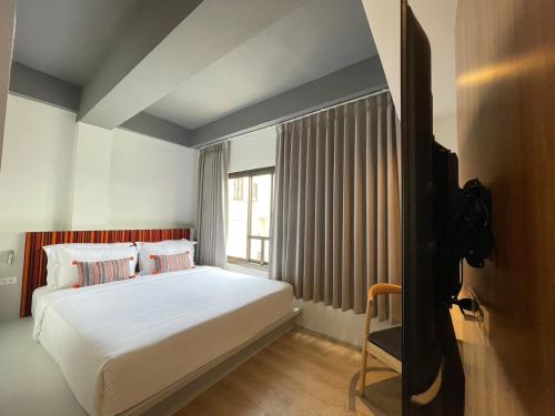 a bedroom with a bed and a large window at At Thaphae Hostel in Chiang Mai