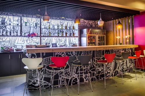 a bar with red chairs and a wall covered in graffiti at Ibis Porto Alegre Assis Brasil in Porto Alegre