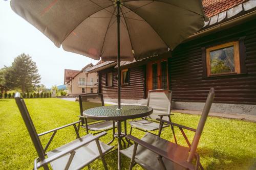 a table and chairs with an umbrella in a yard at Cozy Alpine House in Gozd Martuljek