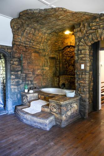 a stone bathroom with a tub in a stone wall at Biggy Best Boutique Hotel & Self Catering Cottages in Howick