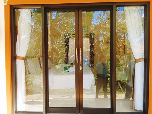 a glass door with a reflection of a person in the window at Balitrees in Selemadeg