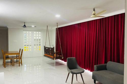 a living room with a red curtain and chairs at Rajamandiram 3BHK AC,Near Sree Padmanabhaswamy Temple, Trivandrum Central in Trivandrum