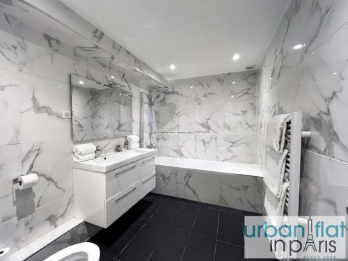 une salle de bain blanche avec une baignoire et un lavabo dans l'établissement Urban Flat 182 - Spacious 4 Bedroom Flat in Paris, à Paris