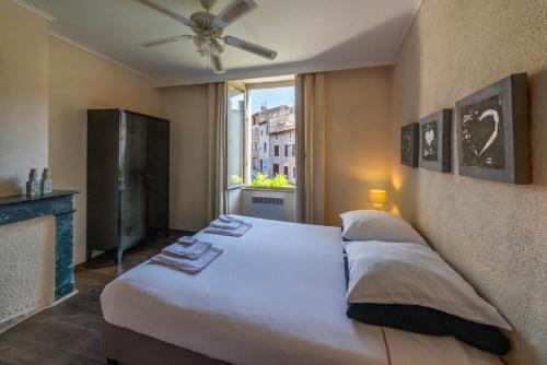 a bedroom with a large white bed with a window at La Maison au Puits in Cordes-sur-Ciel