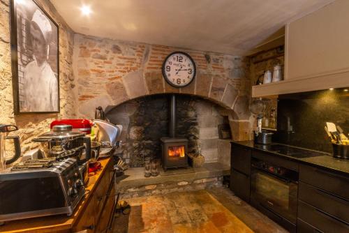 a kitchen with a stove and a clock on the wall at La Maison au Puits in Cordes-sur-Ciel