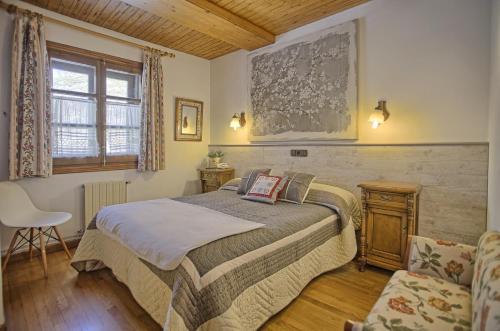 1 dormitorio con 1 cama y 1 silla en San Marsial Benasque Apart Hotel en Benasque