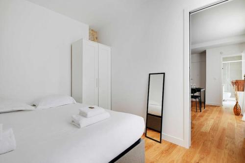 une chambre avec un lit blanc et un miroir dans l'établissement Charming apartment In Le Marais, à Paris
