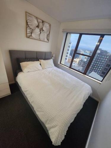 a bedroom with a white bed with a large window at Cosy studio in the heart of the city in Wellington
